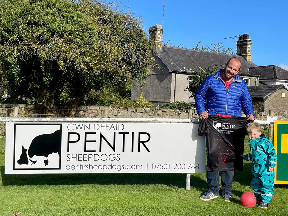 Glynne and Deian Jones of Pentir Sheepdogs  holding a sponserd shirt next to a pentir sheepdogs sign